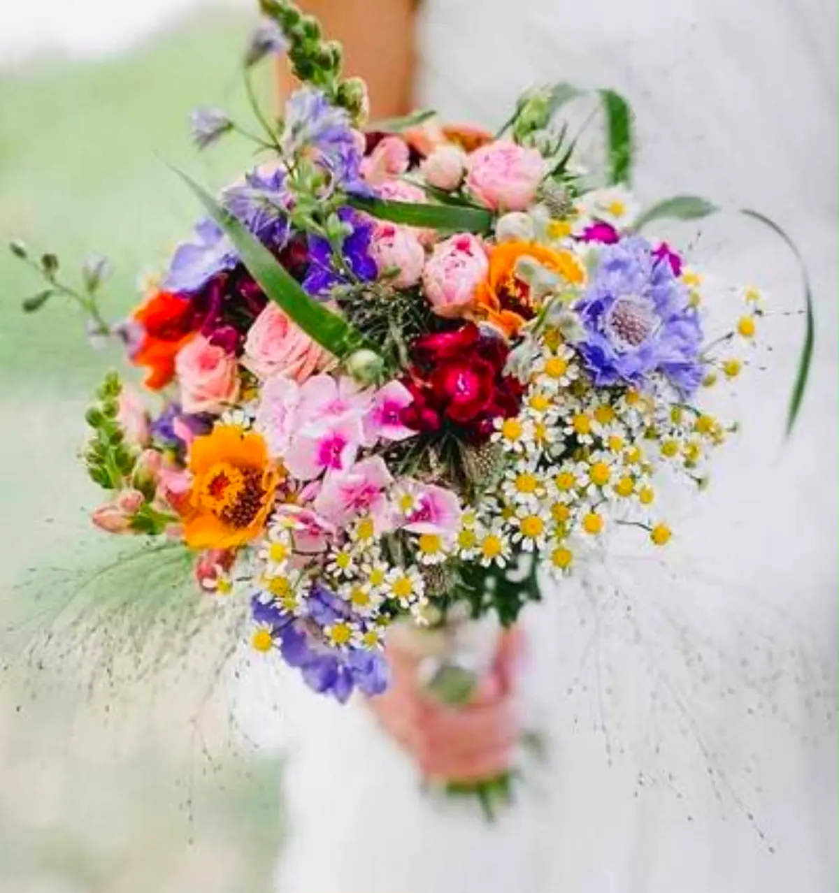 Bruidsboeket van veldbloemen met kamille, ridderspoor en rozen
